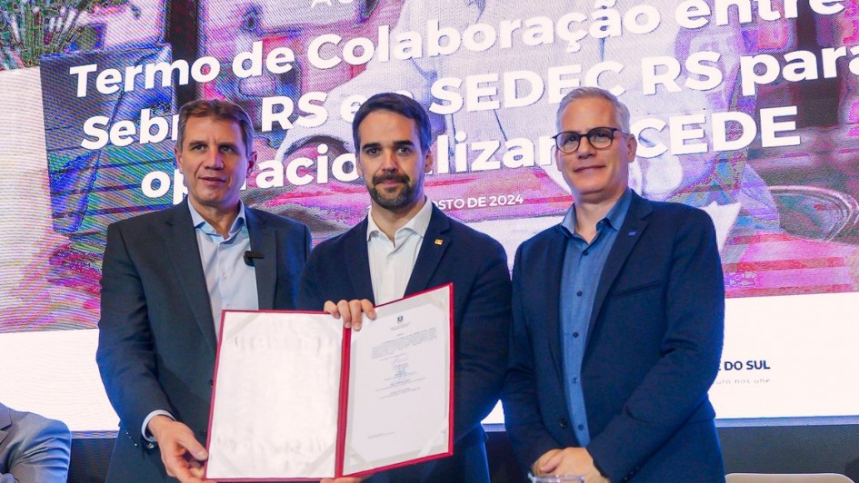 Foto posada, Leite e mais dois homens seguram o documento recém assinado para a retomada do Cede.