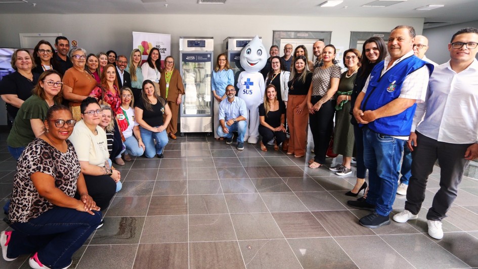 Foto possada de diversas pessoas reunidas em torno de duas câmaras frias para conservação de vacina durante ato de entrega dos equipamentos.