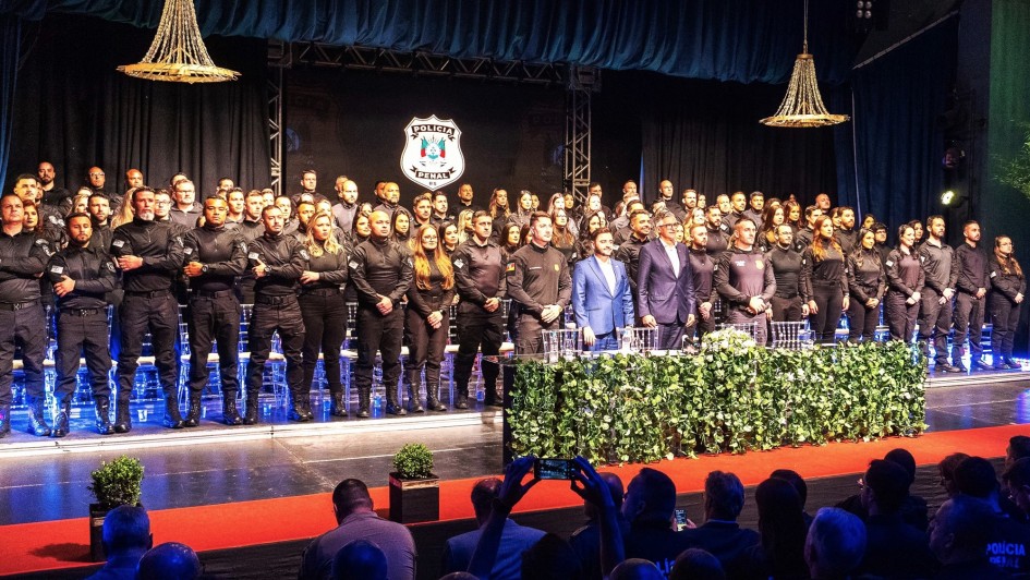 Foto posada dos formandos da polícia penal junto com autoridades em cima do palco na cerimônia formatura.