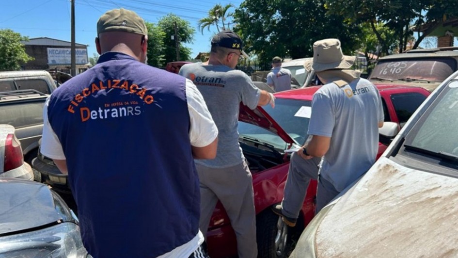 Técnicos do Detran RS fazendo vistoria em veículos.