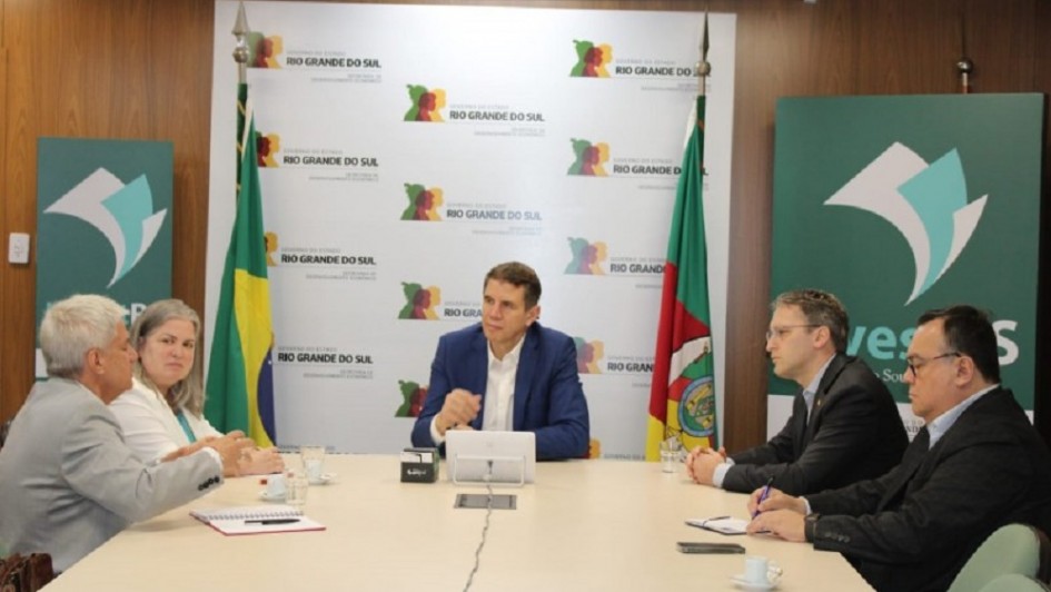 Imagem de uma reunião com cinco pessoas sentadas à mesa.