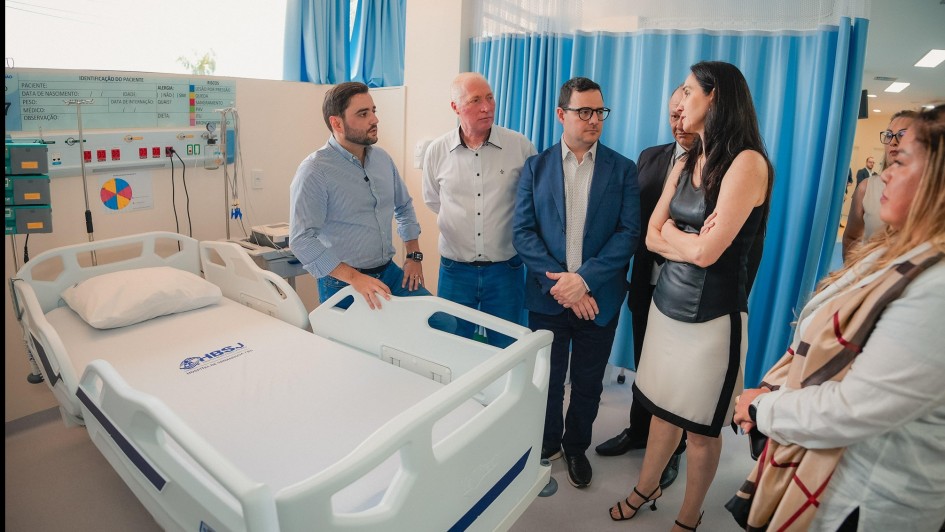 Seis pessoas conversando enquanto observam um dos leitos da nova UTI do Hospital de Sananduva.