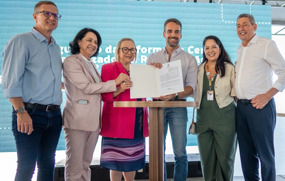 Leite e mais cinco pessoas seguram o documento recém assinado, em foto posada.