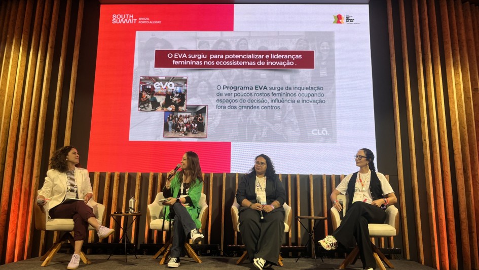 Foto de quatro mulheres sentadas em cadeiras com uma tela grande atrás delas debatendo durante um painel do SSB 2025.