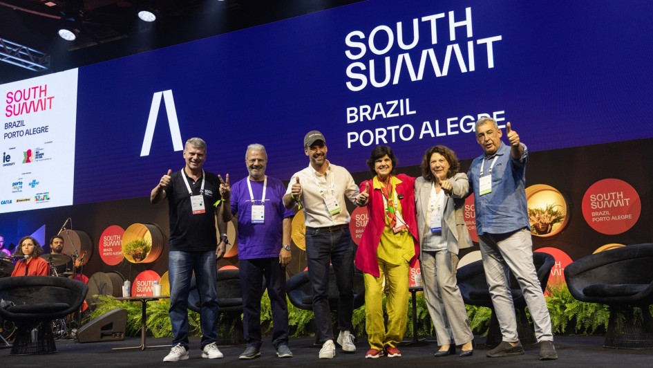 Leite e outras cinco pessoal em pé sobre um palco fazendo sinal de positivo com as mãos na abertura oficial do SSB 2025.