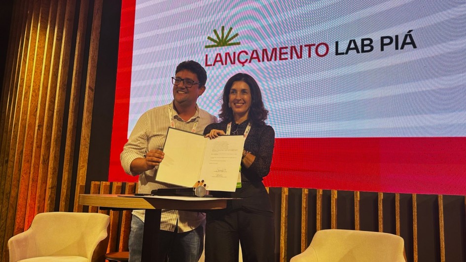 Foto posada em que duas pessoas seguram o documento de lançamento recém assinado.