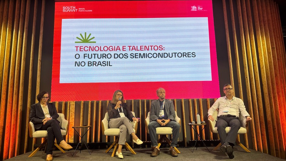 Na foto, há quatro palestrantes (duas mulheres e dois homens) sentados em cadeiras em um palco, vestindo roupas sociais. Ao fundo, na projeção de um painel branco e rosa, está escrito o seguinte título: "Tecnologia e talentos: o futuro dos semicondutores no Brasil".