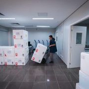 Um homem transporta em um carrinho de mercadorias caixas de vacinas.