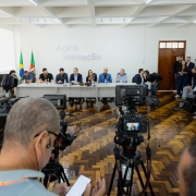 Imagem geral de coletiva sobre gripe aviária em maio de 2025. Na mesa diversas pessoas ligadas ao governo e de costas e nas laterais jornalistas assitiindo.