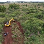 Imagem de uma retroescavadeira fazendo o trabalho de decapagem e nivelamento do terreno no início da construção da Penitenciária de São Borja.