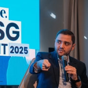 A imagem mostra o vice-governador do Estado, Gabriel Souza, em um painel de discussão. Ele é um homem branco de barba curta, vestindo um terno azul-escuro e camisa clara, sentado em uma poltrona cinza. Com uma mão, ele segura um microfone e com a outra, aponta para frente enquanto fala, com a boca ligeiramente aberta. Ao fundo, um telão azul exibe em branco o logotipo "exame." e as palavras "ESG SUMMIT 2025" em letras grandes. Dois copos de água vazios estão em uma mesa de vidro à frente do telão. Gabriel Souza foi um dos painelistas do evento ESG Summit 2025, que discute o futuro do clima e é promovido pela revista Exame, participando do painel "Eventos climáticos extremos e a necessidade de adaptação".