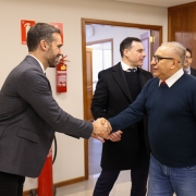 A imagem mostra, em primeiro plano, o governador Eduardo Leite cumprimentando o conselheiro do TCE, Estilac Xavier. Eles estão apertando as mãos e sorrindo. 
