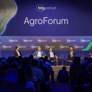 A foto mostra cinco homens sentados em um palco, participando de um painel. O governador do RS, Eduardo Leite, fala ao microfone. A plateia acompanha a atividade. Ao fundo há inscrições repetidas de "btg pactual" e, em tamanho maior, a palavra "AgroForum". 
