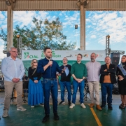Evento comunitário com várias pessoas; destaque para um orador com microfone em frente a banner “RS Social”.