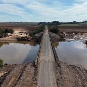 Imagem aérea de uma ponte recuperada sobre o rio Jaguari. As margens estão com sinais de erosão. 