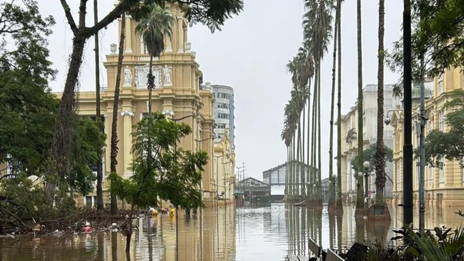Imagem externa do prédio do MARGS em meio às águas da enchente de 2024. Toda a região ao redor do edifício está alagada.