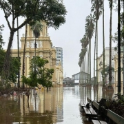 Imagem externa do prédio do MARGS em meio às águas da enchente de 2024. Toda a região ao redor do edifício está alagada.