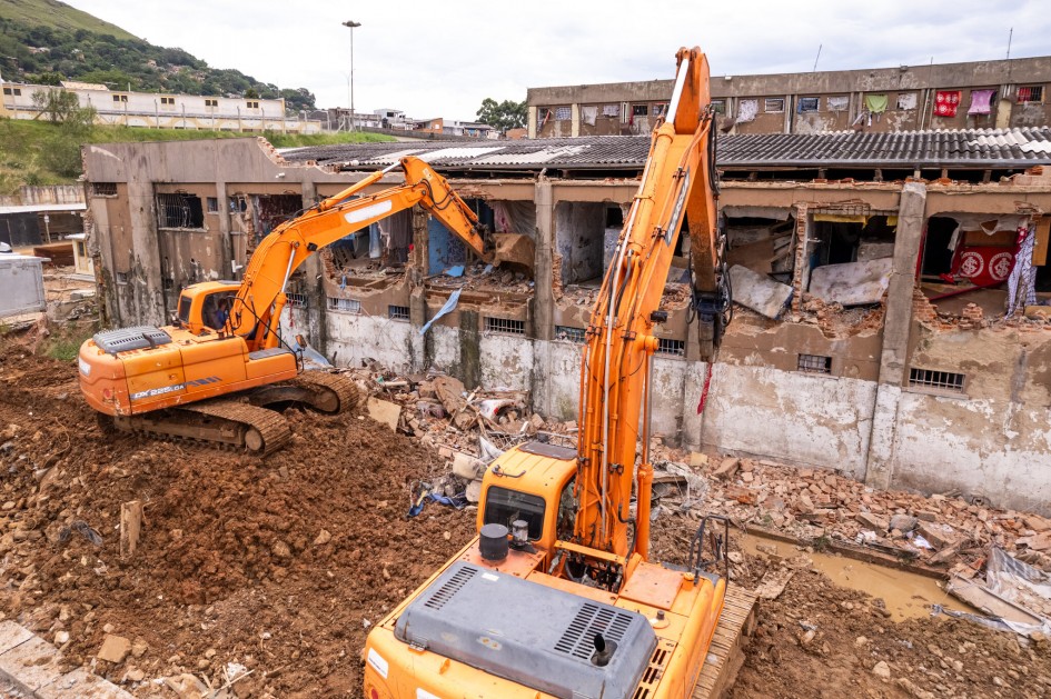 Foto ao ar livre mostra duas máquinas demolindo paredes de concreto da estrutura da Cadeia Pública de POA.