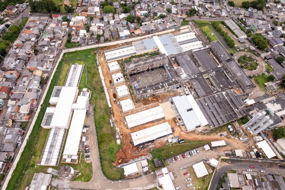 Imagem área da Cadeia Pública de Porto Alegre. Há diversos edifícios retangulares em demolição e em construção. Ao redor, há casas e ruas da cidade.