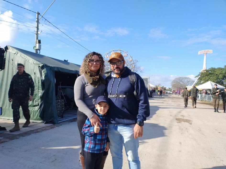 foto mostra o casal Marceano e Kátia Corrêia, acompanhado do filho Enrico num dos corredores do parque da Expointer