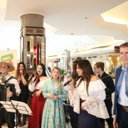 Um grupo de cantores e músicos nativistas se apresenta no shopping. Eles vestem roupas tradicionais gaúchas. No canto direito da imagem, está o secretário de desenvolvimento econômico, de lenço e bombacha. 