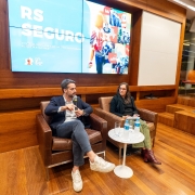 Governador Eduardo Leite está sentado em uma poltrona ao lado de outra palestrante do evento.