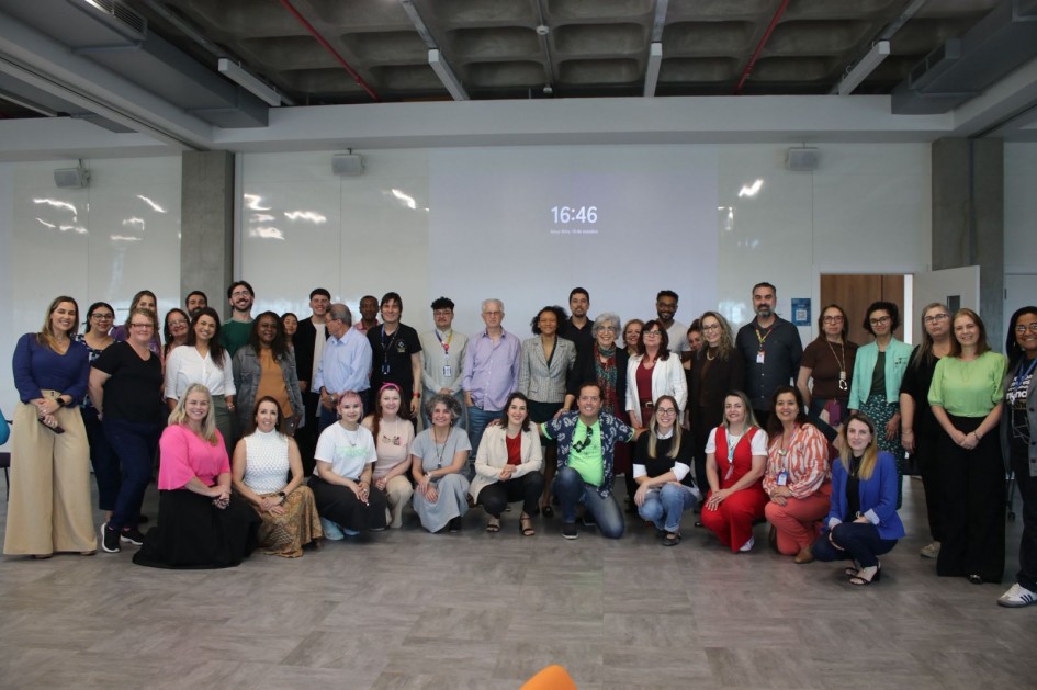 Foto de grupo com todos os participantes do evento. Educadores, gestores e convidados posam sorridentes após o encerramento das atividades do ciclo, em uma sala ampla e bem iluminada.