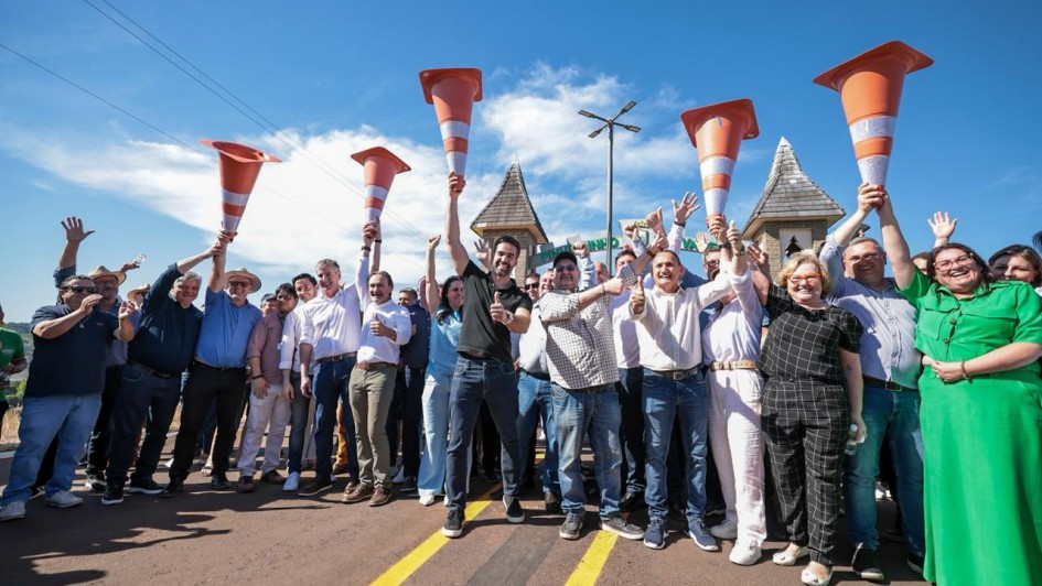 Foto posada de Leite ao centro,  com várias pessoas ao redor, erguendo cones de trânsito na estrada, em comemoração.