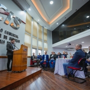 O vice-governador Gabriel Souza aparece em pé, falando ao microfone em um púlpito com o logotipo “ACIS”. À frente dele, há várias pessoas sentadas em cadeiras vermelhas, observando a apresentação.