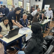 Foto mostra sala montada para o atendimento, tendo trabalhadores e moradores da cidade de Bagé trocando informações em mesas com computadores