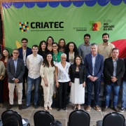 oto de grupo registra o lançamento do plano de ocupação da Escola Técnica CRIATEC, primeira voltada ao audiovisual e à economia criativa no Rio Grande do Sul. A imagem mostra autoridades, educadores e profissionais da cultura reunidos diante do painel institucional da CRIATEC, da Secretaria da Educação e do Governo do Estado do Rio Grande do Sul. Todos posam sorridentes em ambiente interno, com decoração colorida e iluminação natural.