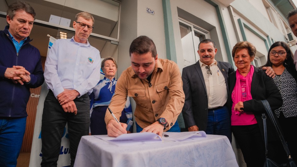 Foto mostra vice-governador Gabriel Souza assinando documento sob o olhar de integrantes da comunidade