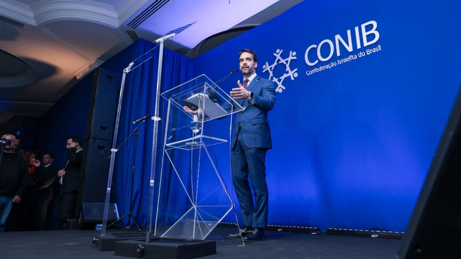 Foto mostra governador Eduardo Leite de pé em discurso na 56ª Convenção da Confederação Israelita do Brasil (Conib)