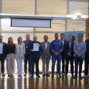 Foto mostra 16 pessoas perfiladas, durante ato para assinatura para o Programa Bônus Mais Leite. Ao centro, secretário Vilson Covatti, segura documento