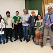 A imagem mostra sete pessoas em pé, posando para a foto e segurando o troféu do prêmio Prêmio Minuano de Literatura 2025. 