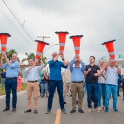 Uma foto externa de um grupo de cerca de 18 homens posando para a câmera em frente a um prédio moderno, possivelmente em um campus de pesquisa ou inovação. A maioria dos homens veste roupas casuais de negócios, como blazers, camisas polo ou casacos leves.

O grupo está reunido em frente a uma placa de sinalização de metal cinza com o logotipo e o nome: "NEBRASKA INNOVATION CAMPUS" e "Greenhouse Innovation Center" em letras grandes, indicando o local da visita.

O edifício ao fundo é moderno, com fachada de cor clara (cinza claro e bege) e amplas janelas horizontais escuras. O gramado em primeiro plano está verde e há uma árvore frondosa e uma luminária de rua no canto direito. O céu está nublado, e a comitiva parece estar em uma missão de pesquisa em irrigação ou tecnologia agrícola nos EUA.