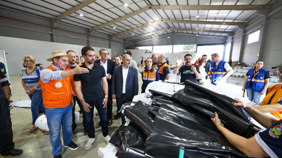 Foto mostra o governador Eduardo Leite, juntamente com gestores e autoridades, em local de prestação de apoio humanitário