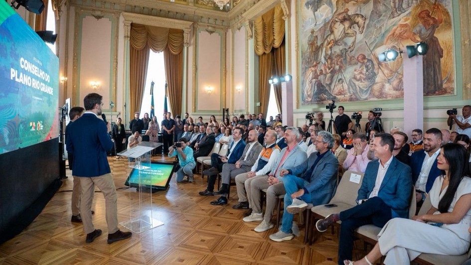 Foto mostra governador Eduardo Leite e pelo vice Gabriel Souza, na reunião do Conselho do Plano Rio Grande, ambos em pé falando aos participantes, no Palácio Piratini.