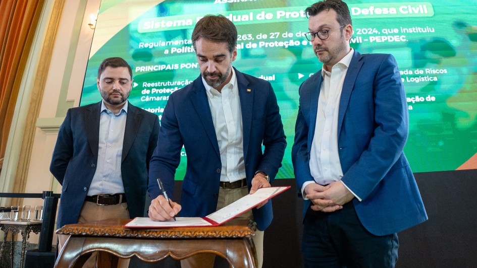 Foto mostra o governador Eduardo Leite em ato de assinatura, ao centro, tendo à esquerda o vice-governador Gabriel Souza e à direita o secretário chefe da Casa Civil, Artur Lemos