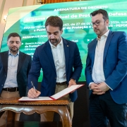 Foto mostra o governador Eduardo Leite em ato de assinatura, ao centro, tendo à esquerda o vice-governador Gabriel Souza e à direita o secretário chefe da Casa Civil, Artur Lemos