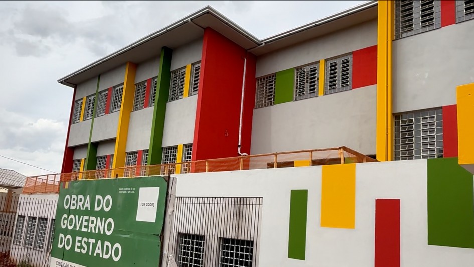 Imagem mostra a fachada da escola Margarida Pardelhas, com detalhes coloridos e placa de obras pelo governo do Estado.