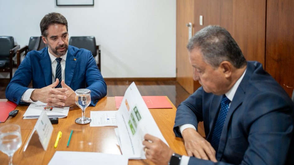 Foto de Leite, sentado junto à mesa e à esquerda do quadro, falando com as mãos apoiadas na mesa. À direita Rui Costa ouve, também sentado e olhando um documento.