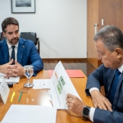 Foto de Leite, sentado junto à mesa e à esquerda do quadro, falando com as mãos apoiadas na mesa. À direita Rui Costa ouve, também sentado e olhando um documento.