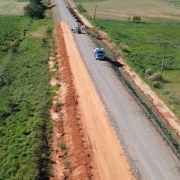 Foto aérea de uma estrada simples, de mão dupla, em meio à vegetação baixa.