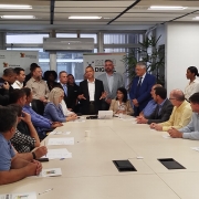 Foto mostra reunião de representantes municipais na Secretaria de Habitação e Regularização Fundiária, tendo ao centro o secretário Carlos Gomes.