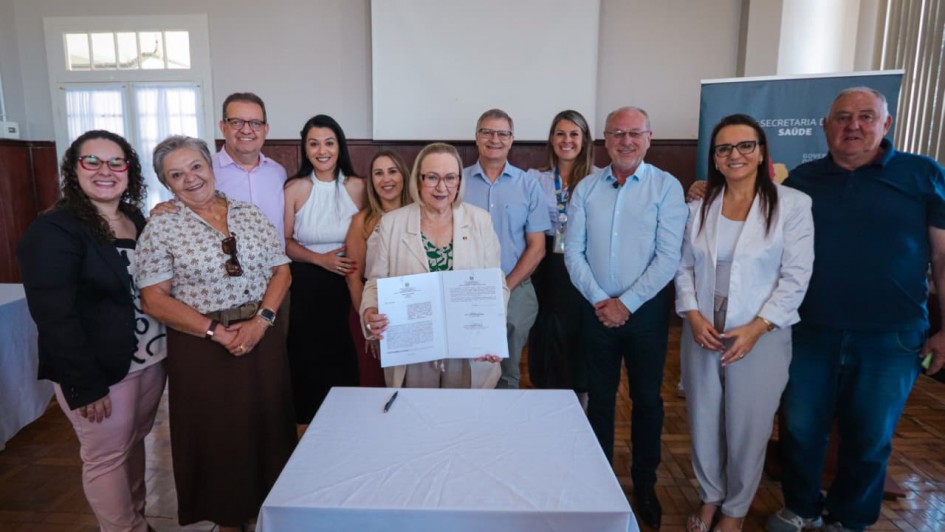 Foto mostra ato de assinatura de conv&ecirc;nios com hospital de Rio Pardo, tendo a secret&aacute;ria da Sa&uacute;de, Arita Bergmann, ao centro, segurando documento