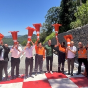 Grupo de pessoas em estrada rec&eacute;m-pintada, segurando cones de tr&acirc;nsito sobre a cabe&ccedil;a em gesto comemorativo.