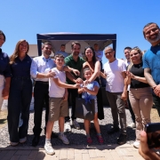 Foto posada em ambiente aberto, onde Leite aparece ao centro, de p&eacute;, com cinco pessoas tamb&eacute;m de p&eacute; enfileiradas de cada lado. Leite entrega uma chave para duas crian&ccedil;as.