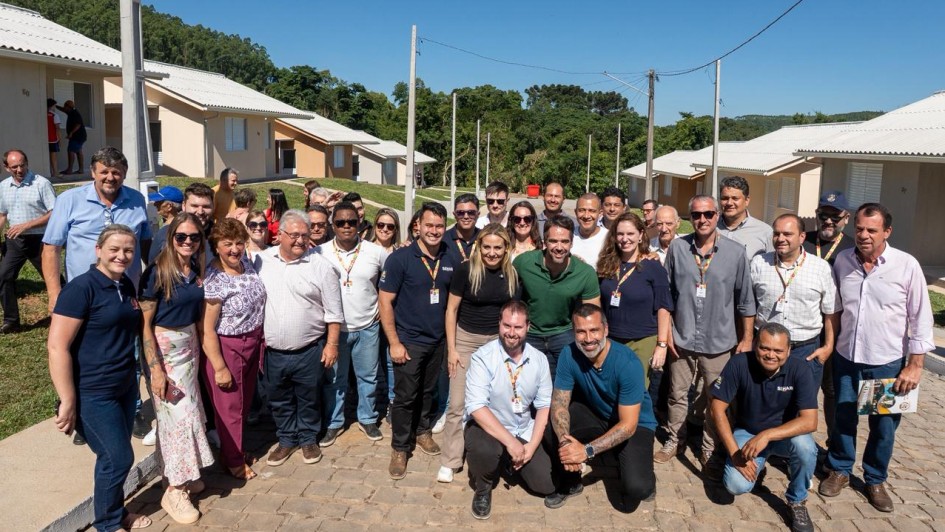 Foto mostra grupo reunido em frente &agrave;s casas com governador e secret&aacute;rios. 