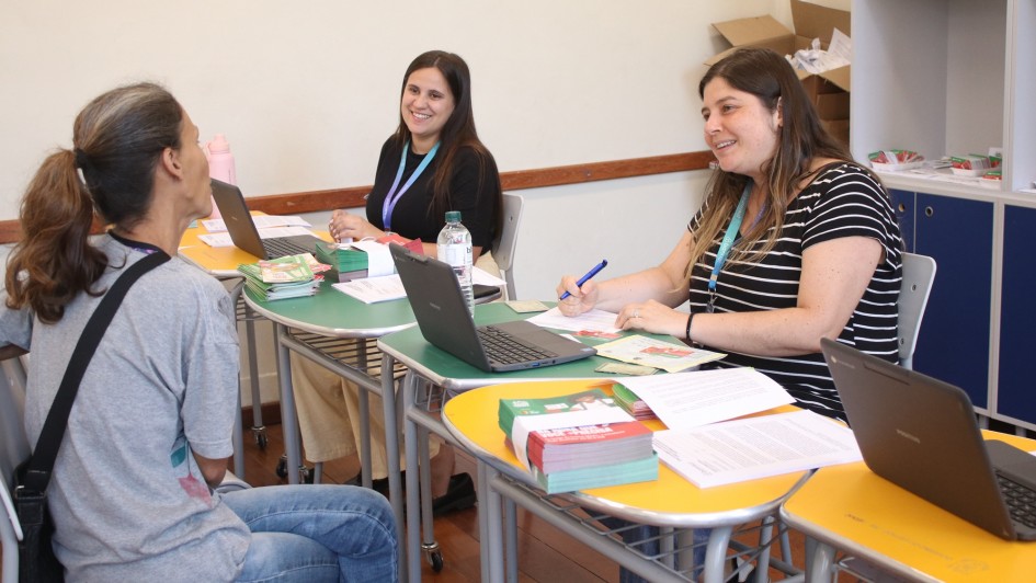 Foto mostra servidoras atendendo m&atilde;e de aluno.